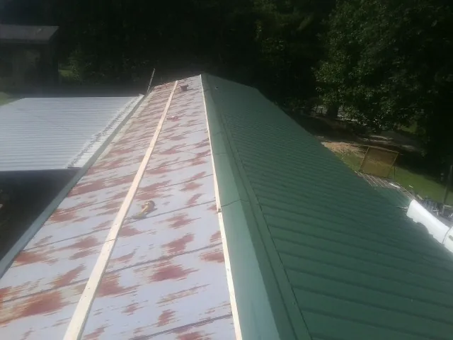 Old rusted panels beside newly installed green metal roofing — Wind Damage Roof Repair by Roofing Brothers in Elkhorn