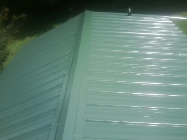 New green metal panels meeting at the ridge of a roof — Flat Roof Repair work by our crew in Elkhorn