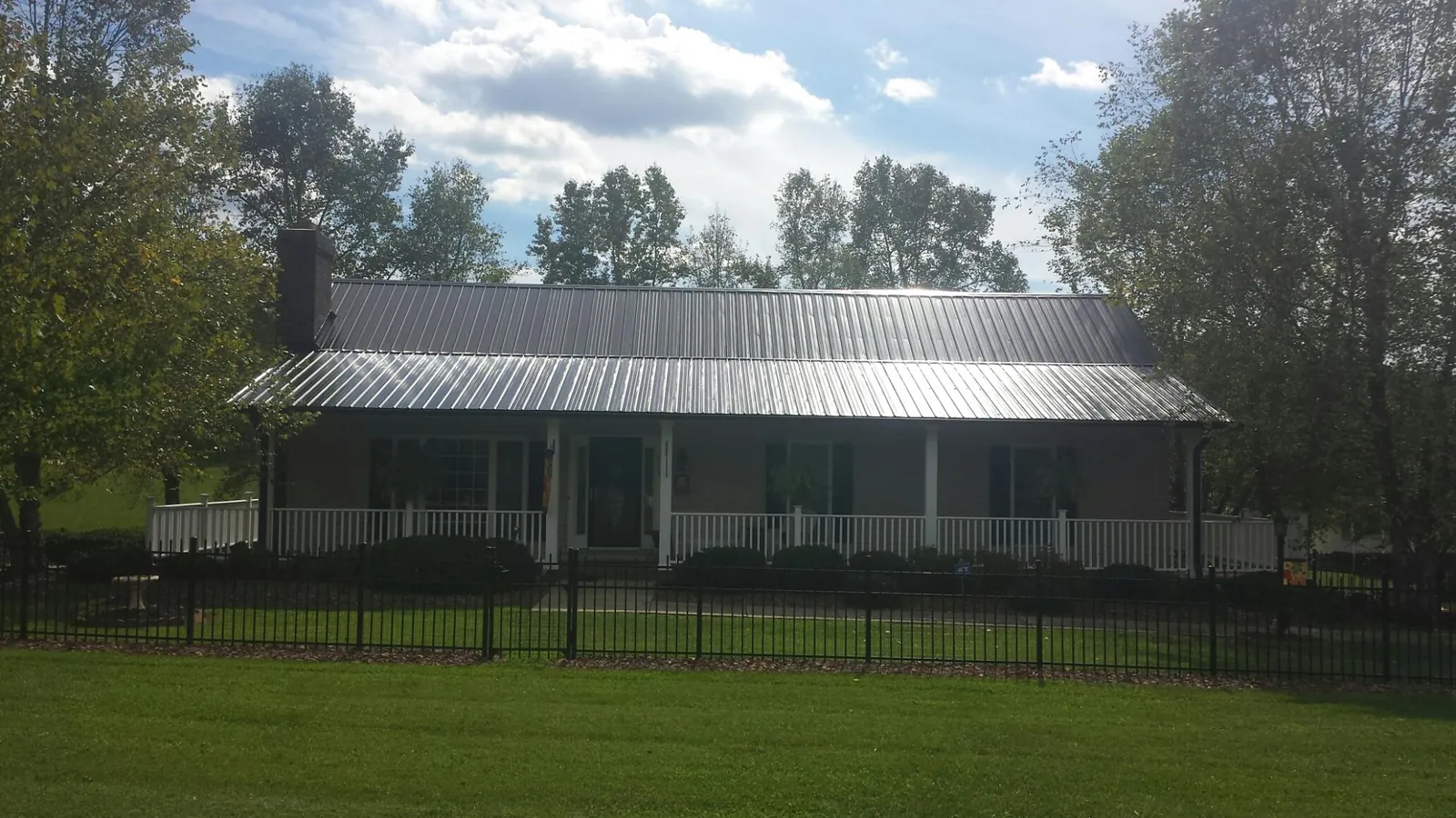 Gray metal roof on a brick ranch with a full width front porch — Gutter Guard Installation work by our crew in Elkhorn