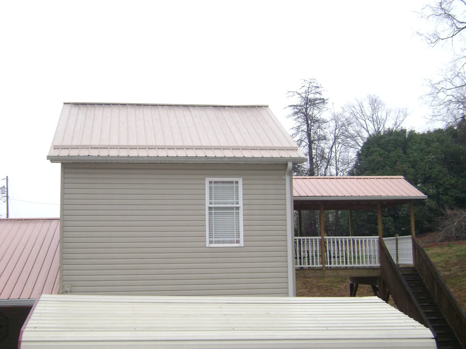 Tan metal roofs on a two story addition and attached porch, from a Roof Replacement job in Elkhorn